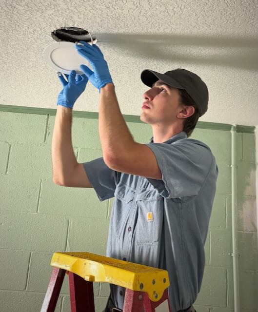 Licensed electrician installing a ceiling light fixture in a residential setting